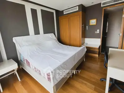 Spacious bedroom with modern furnishings and wooden flooring in a stylish apartment.
