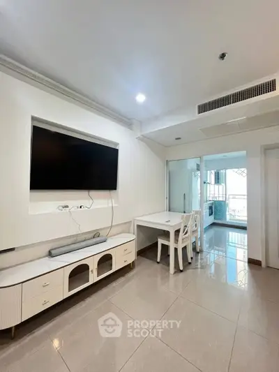 Modern living room with sleek TV setup and dining area, featuring glossy tiled floors and bright lighting.