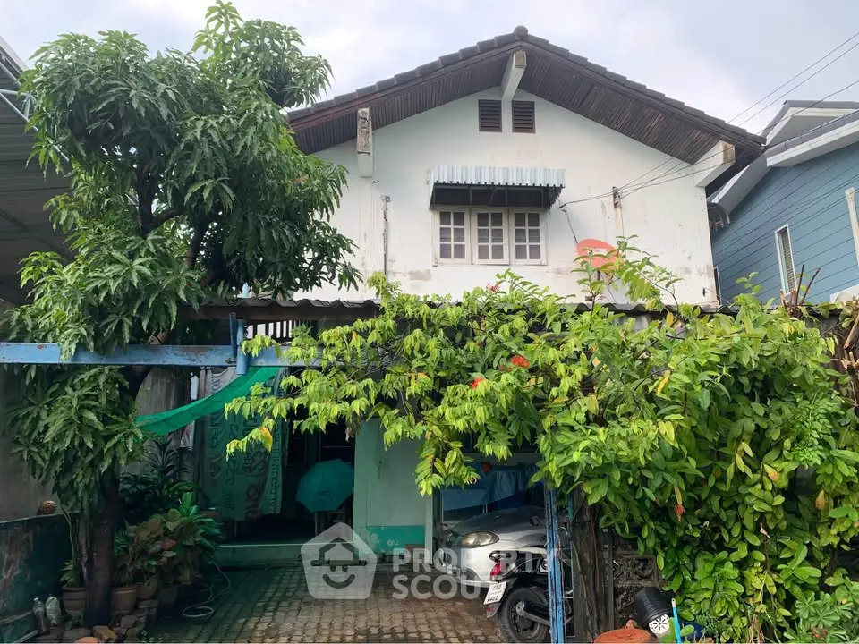 Charming two-story house with lush greenery and spacious driveway in a serene neighborhood.