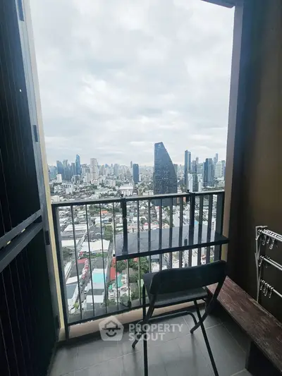 Stunning cityscape view from a high-rise balcony with modern chair and railing.