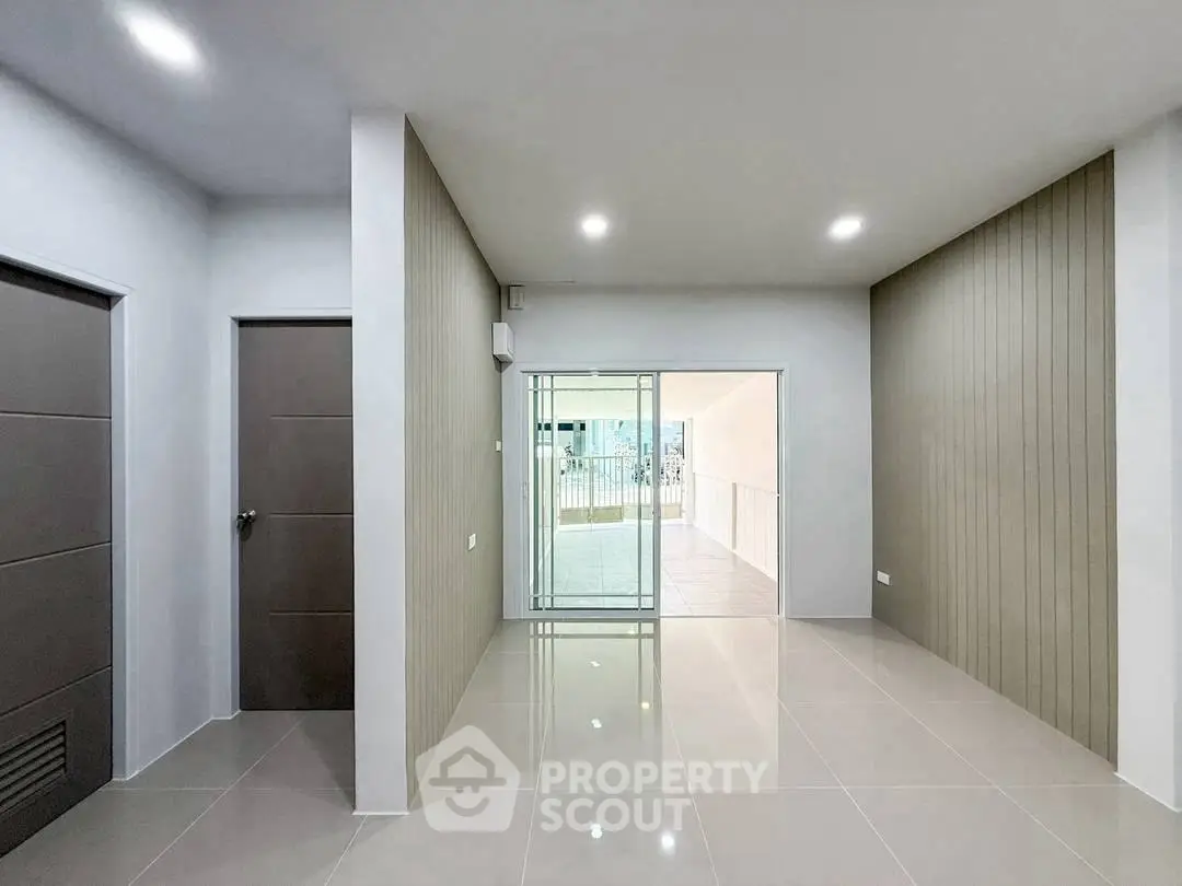 Spacious modern interior with sleek tile flooring and glass doors leading to a balcony.