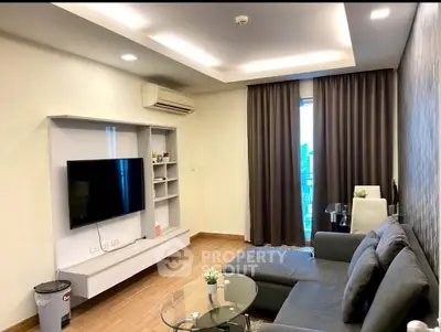 Modern living room with sleek furniture and large TV, featuring a cozy ambiance and stylish decor.