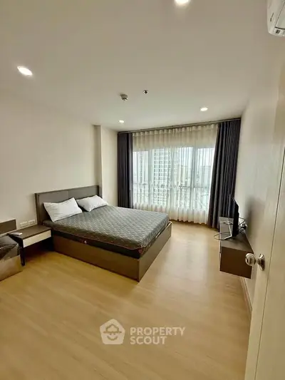Spacious bedroom with modern decor and large windows offering natural light.