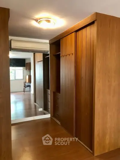 Spacious wooden walk-in closet with mirrored doors and elegant lighting