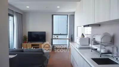 Modern open-layout living room with kitchen, featuring sleek cabinetry and cozy seating area.