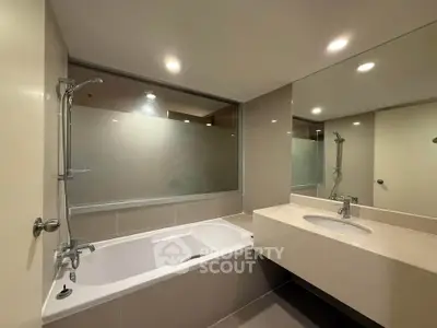 Modern bathroom with sleek design featuring a bathtub and large mirror.
