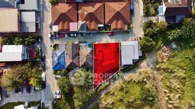 Aerial view of residential area with highlighted plot for sale, showcasing potential for development in a vibrant neighborhood.
