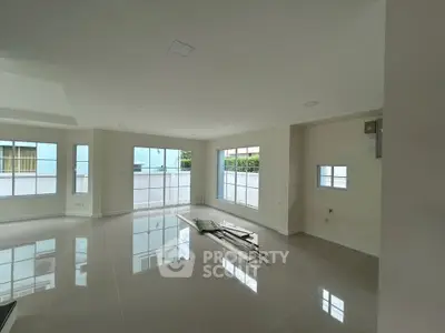 Spacious unfurnished living room with large windows and glossy tiled floors.