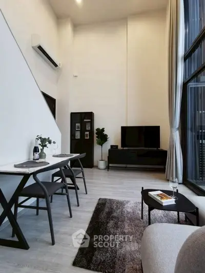 Modern living room with high ceiling, large windows, and stylish decor