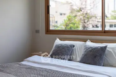 Cozy bedroom with large window and stylish bedding, offering a serene and inviting atmosphere.