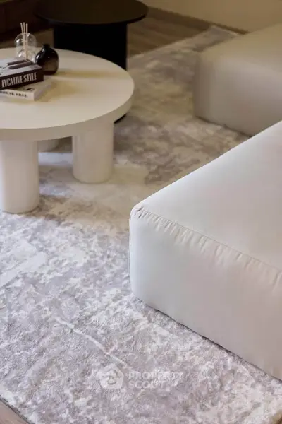 Modern living room with plush white sofa and stylish round coffee table on a textured rug.
