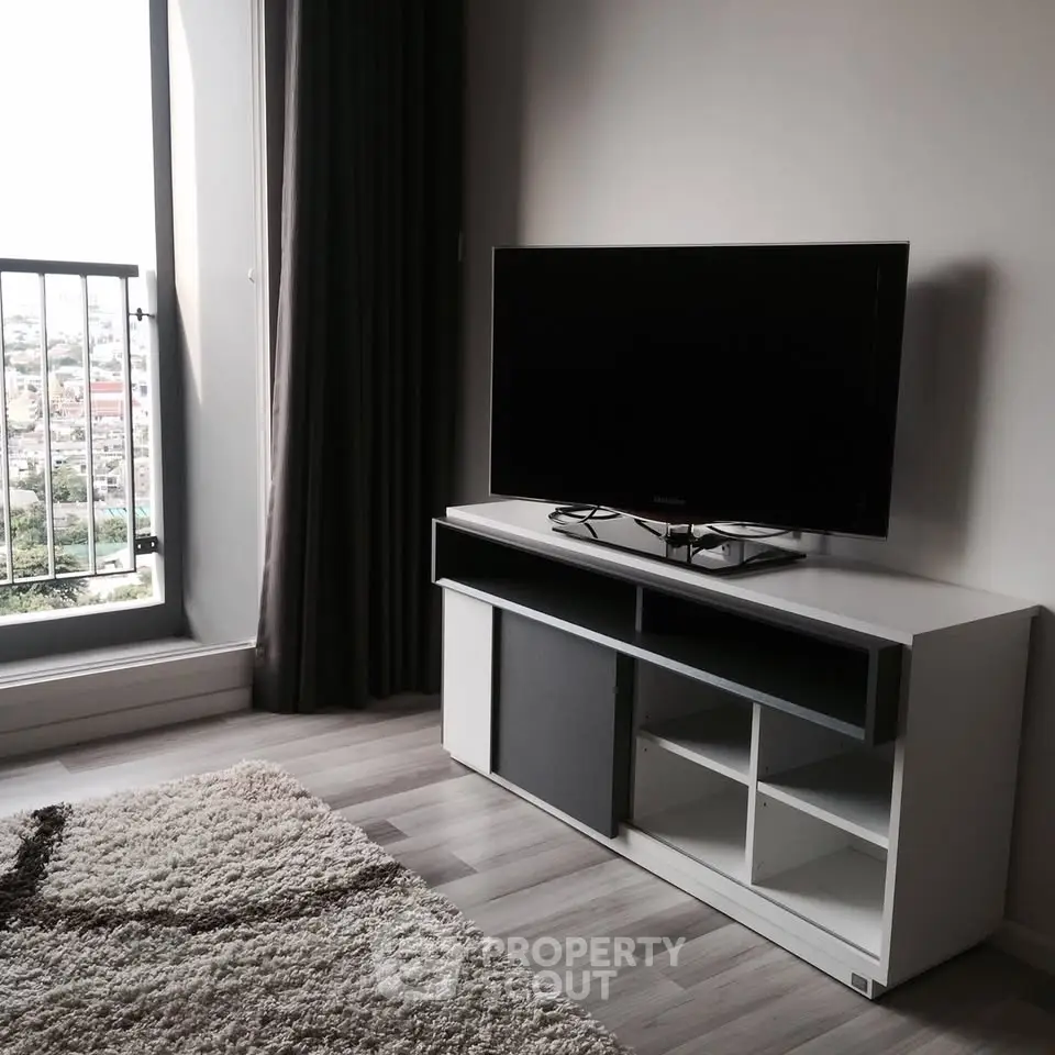 Modern living room with sleek TV stand and large window offering city view.
