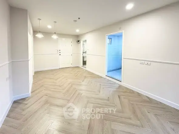 Spacious modern living room with elegant herringbone flooring and bright lighting.