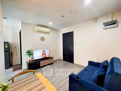Modern living room with blue sofa, TV, and air conditioning in a cozy apartment.