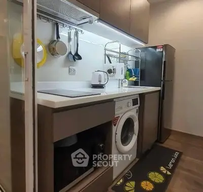Modern kitchen with washing machine and sleek appliances in compact layout.