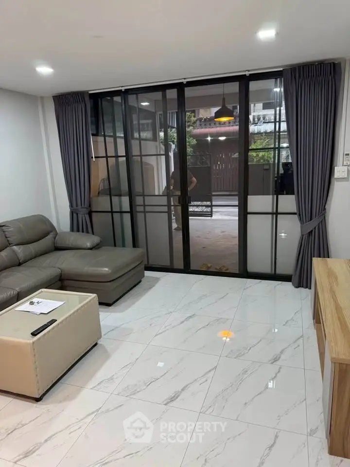Modern living room with sleek furniture and large glass doors leading to a patio, perfect for relaxation.