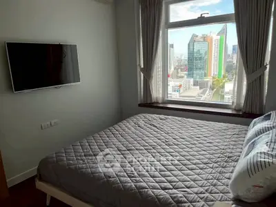 Modern bedroom with city view and wall-mounted TV in a high-rise apartment.