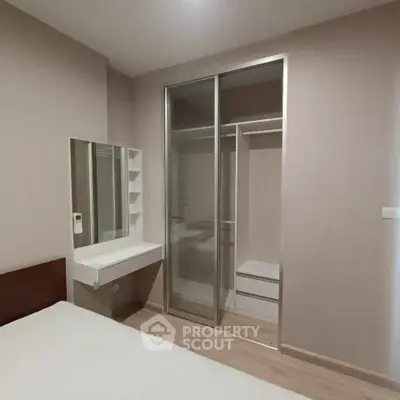 Modern bedroom with sleek sliding wardrobe and minimalist vanity in a stylish apartment.