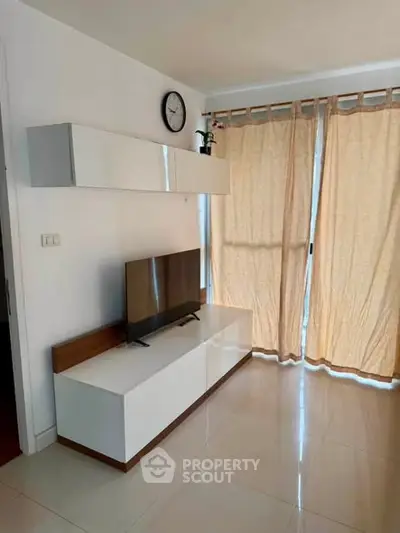 Modern living room with sleek TV stand and large windows with curtains.