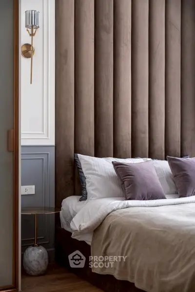 Luxurious bedroom with plush velvet headboard and elegant lighting, perfect for relaxation.