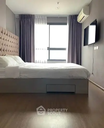 Modern bedroom with stylish decor, large window, and wall-mounted TV in a cozy apartment.