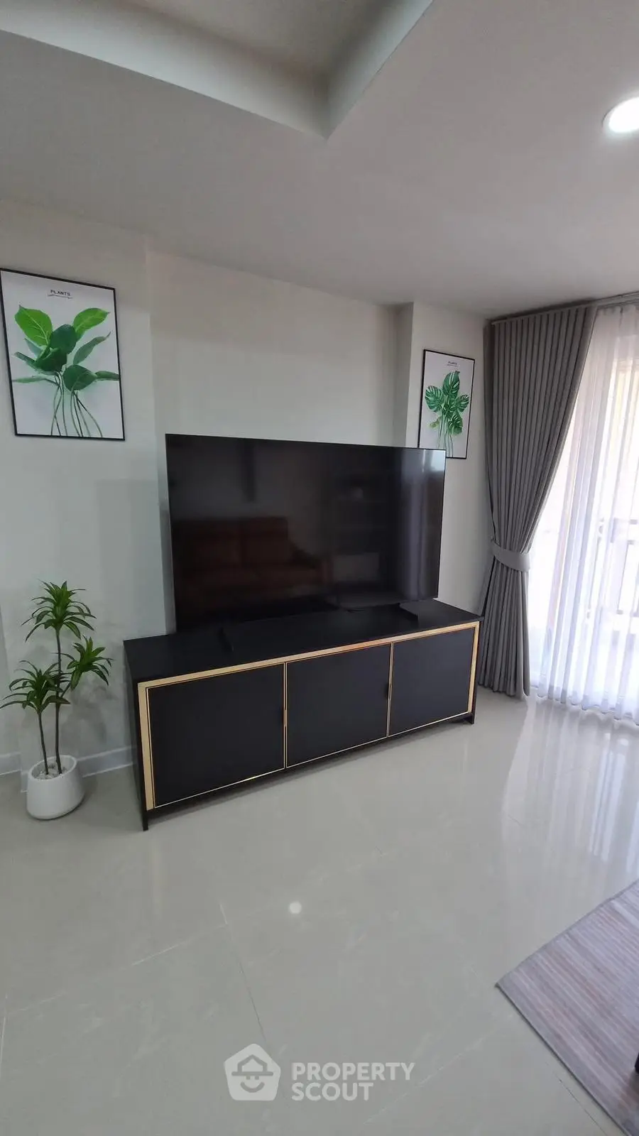 Modern living room with sleek TV stand and large flat-screen TV, complemented by elegant curtains and decor.