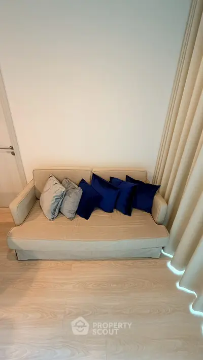 Stylish living room with cozy beige sofa and vibrant blue cushions, perfect for relaxation.