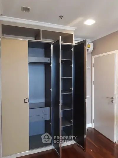 Spacious modern wardrobe with open doors in a stylish bedroom, showcasing ample storage and sleek design.