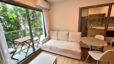 Charming living room with balcony access and modern kitchen in cozy apartment.