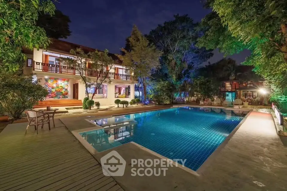 Luxurious villa with illuminated pool and lush garden at night