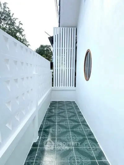 Charming outdoor balcony with green tiled flooring and white privacy wall.