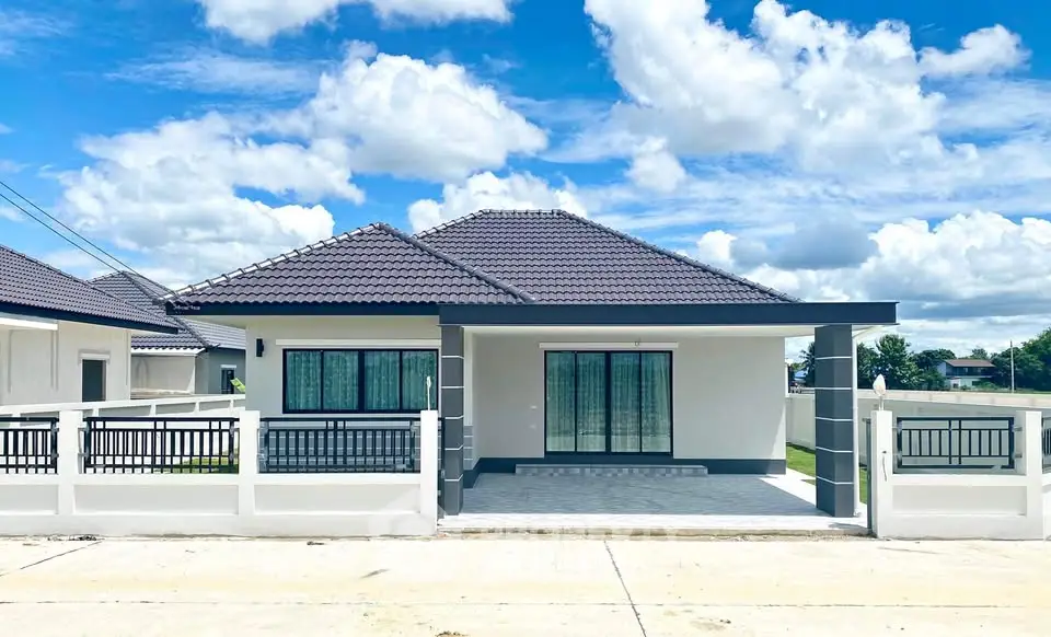 Charming modern house with tiled roof and spacious driveway under a bright blue sky.