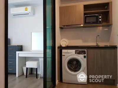 Modern apartment interior with washing machine and microwave in compact kitchen area.