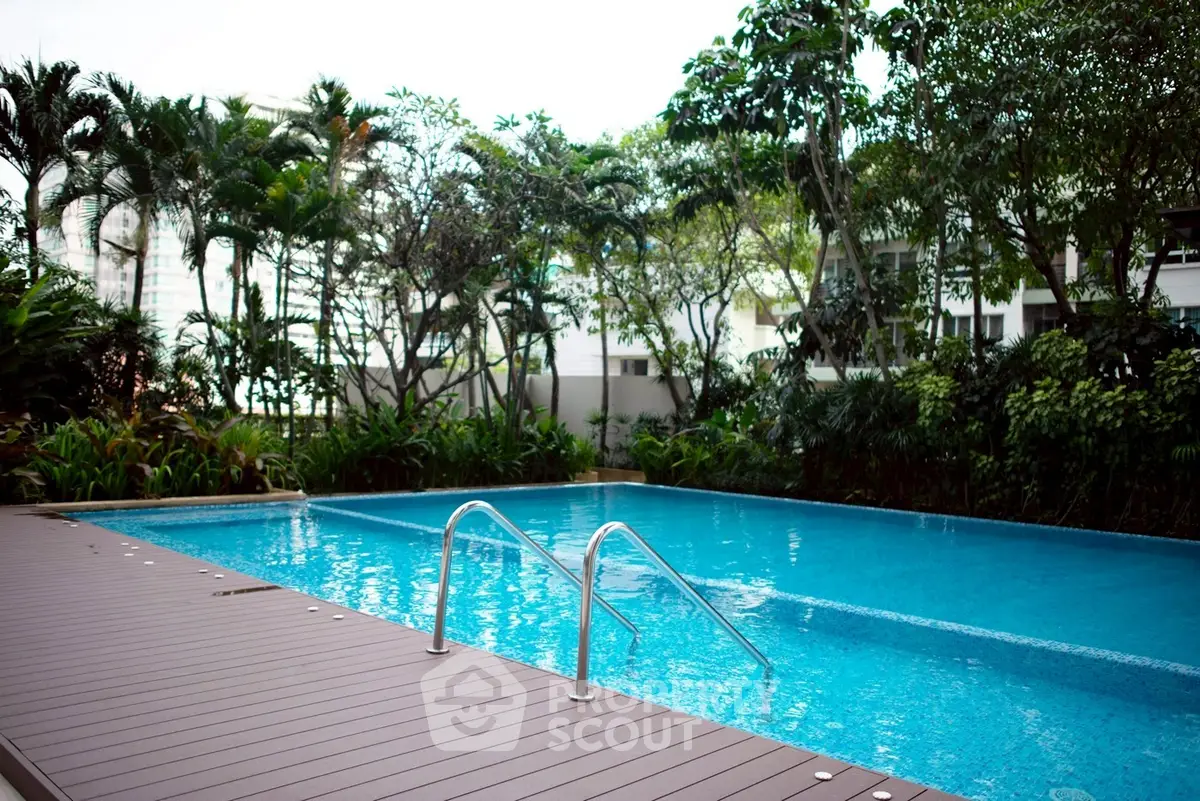 Luxurious outdoor pool surrounded by lush greenery in a modern residential complex.