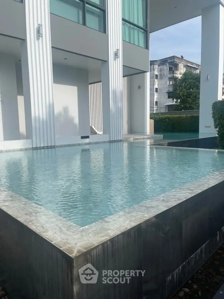 Luxurious modern building with a sleek pool and elegant architecture.