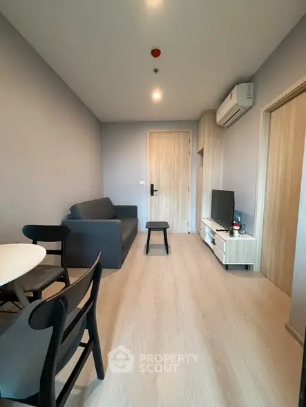 Modern living room with sleek furniture and minimalist design, featuring a cozy sofa and flat-screen TV.