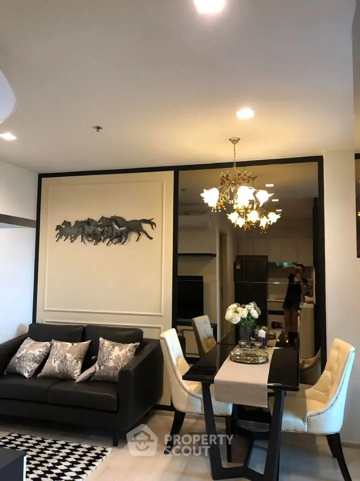 Elegant living room with modern decor and dining area, featuring stylish lighting and wall art.