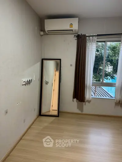 Spacious empty room with air conditioning and large window, perfect for customization.