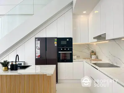 Modern kitchen with sleek white cabinetry and marble countertops under a staircase