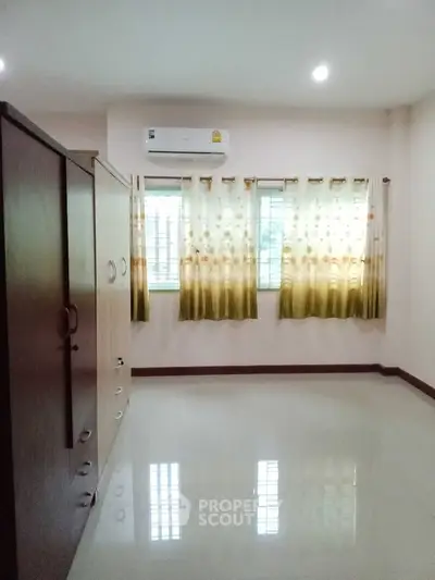 Spacious bedroom with large wardrobe and air conditioning, featuring elegant curtains and glossy flooring.
