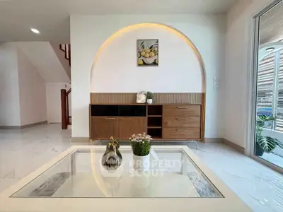 Modern living room with stylish decor and elegant furniture, featuring a glass coffee table and wall art.