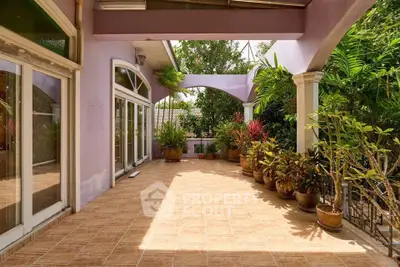 Spacious tiled balcony with lush greenery and elegant archways in a serene setting.