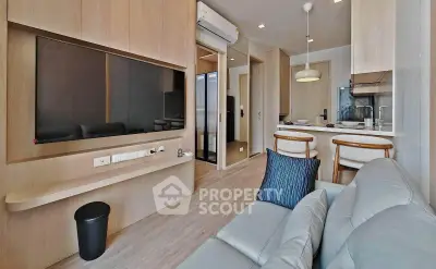 Modern living room with open kitchen, featuring sleek wooden cabinetry and contemporary furnishings.