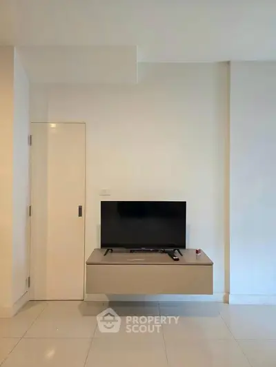 Modern minimalist living room with sleek TV stand and wall-mounted television.