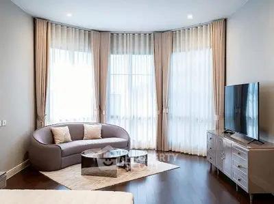 Luxurious living room with elegant curved sofa and large TV, perfect for relaxation.