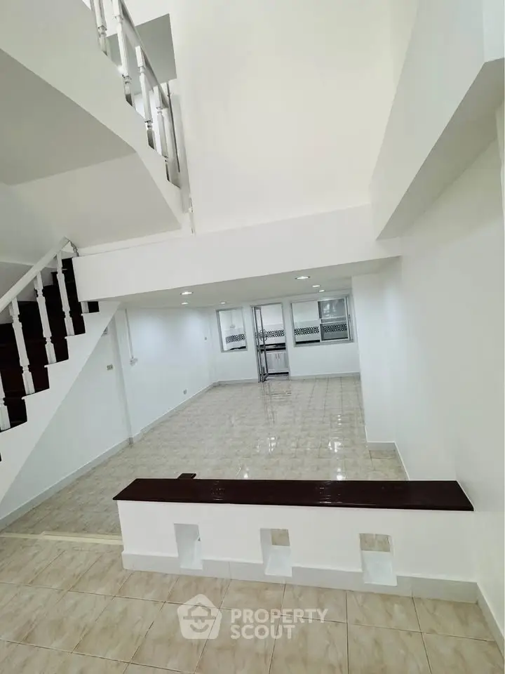 Spacious open-plan living area with modern staircase and tiled flooring, perfect for contemporary living.
