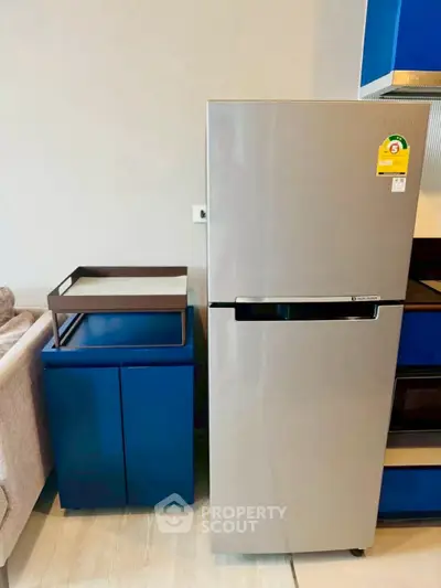 Modern kitchen with sleek stainless steel refrigerator and stylish blue cabinetry.