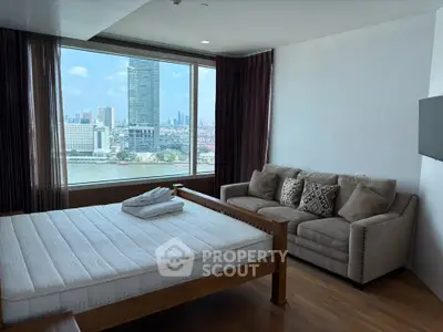 Spacious bedroom with stunning city and river view, featuring a cozy sofa and large window.