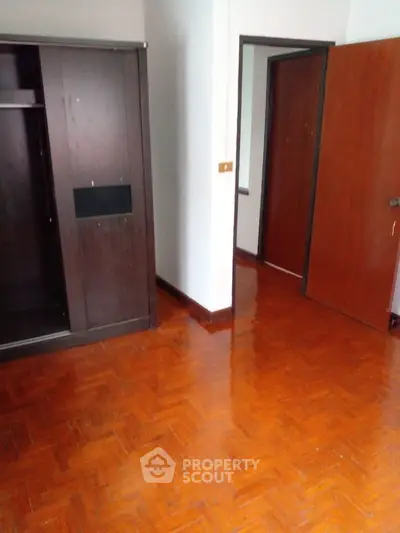 Spacious empty room with wooden flooring and built-in wardrobe
