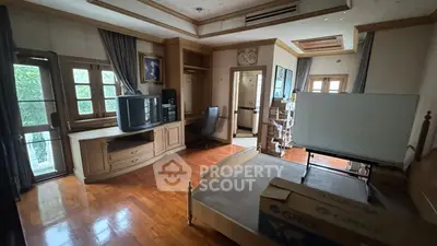 Spacious bedroom with wooden flooring and large windows in a luxurious home.